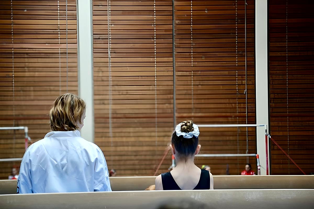 Carolane, entraîneuse, assise avec sa gymnaste face au plateau