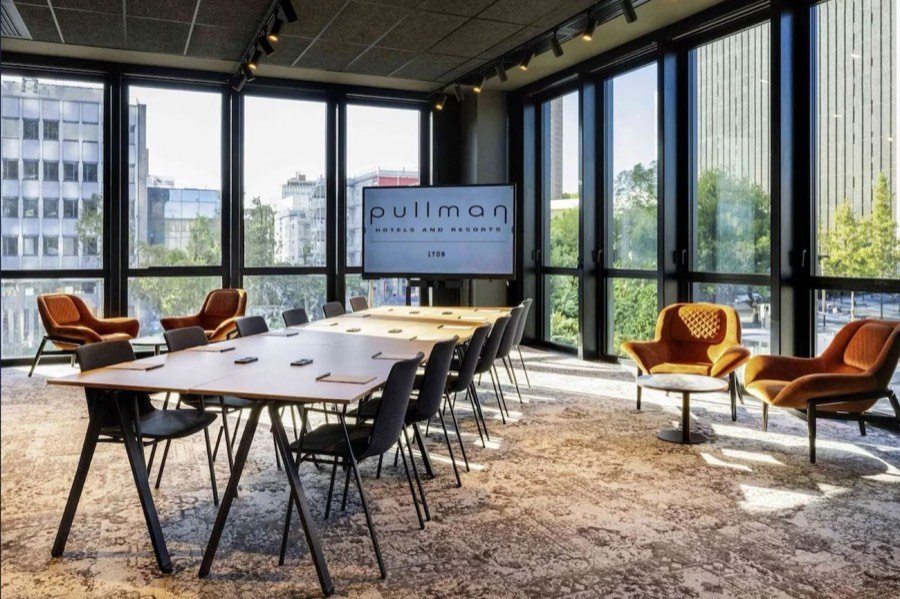 Le studio du Pullman Lyon Part-Dieu, tables en U face à un grand écran, baies vitrées sur la ville